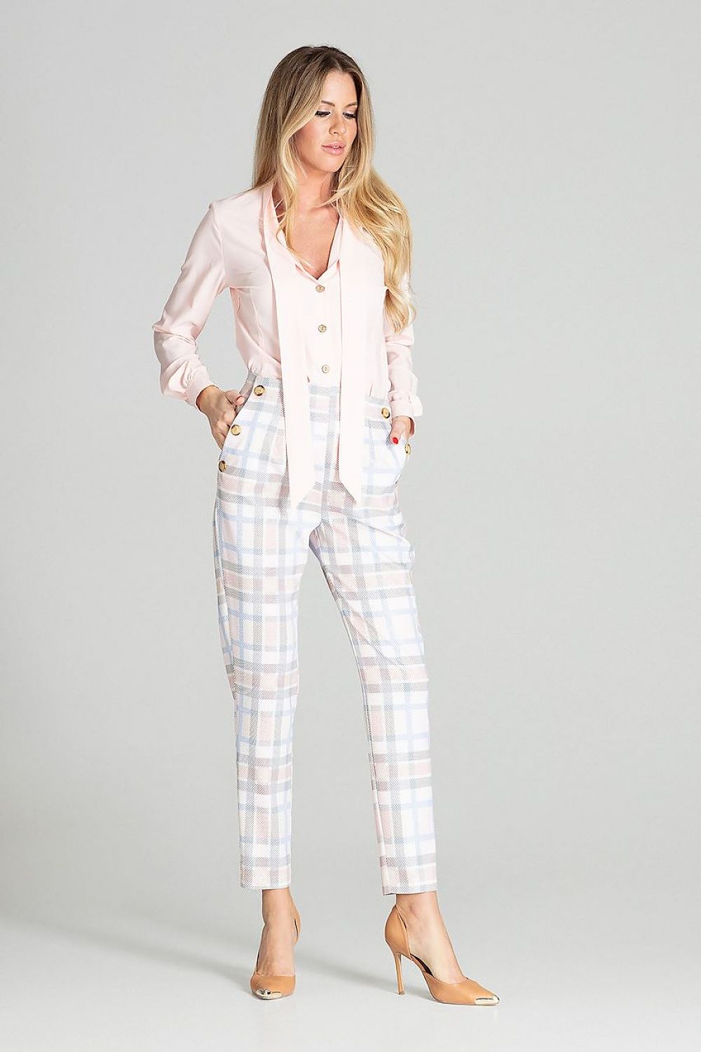 Woman wearing a light pink suit with plaid pants on a gray background
