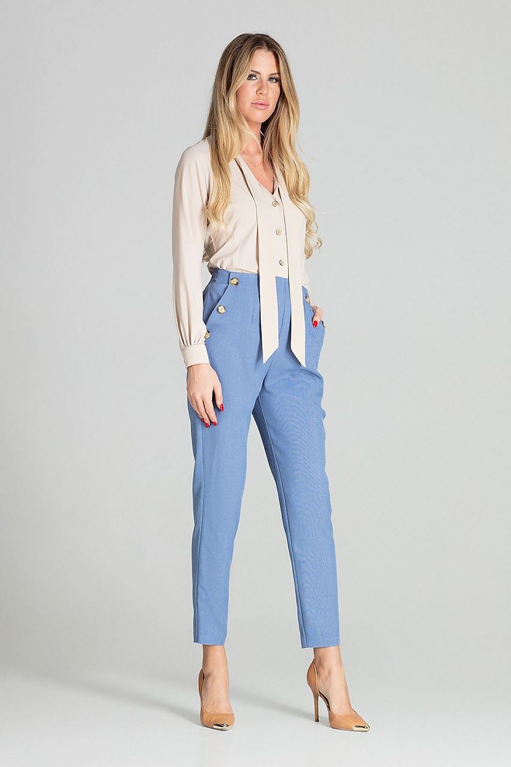 Woman wearing a white blouse and blue pants on a gray background