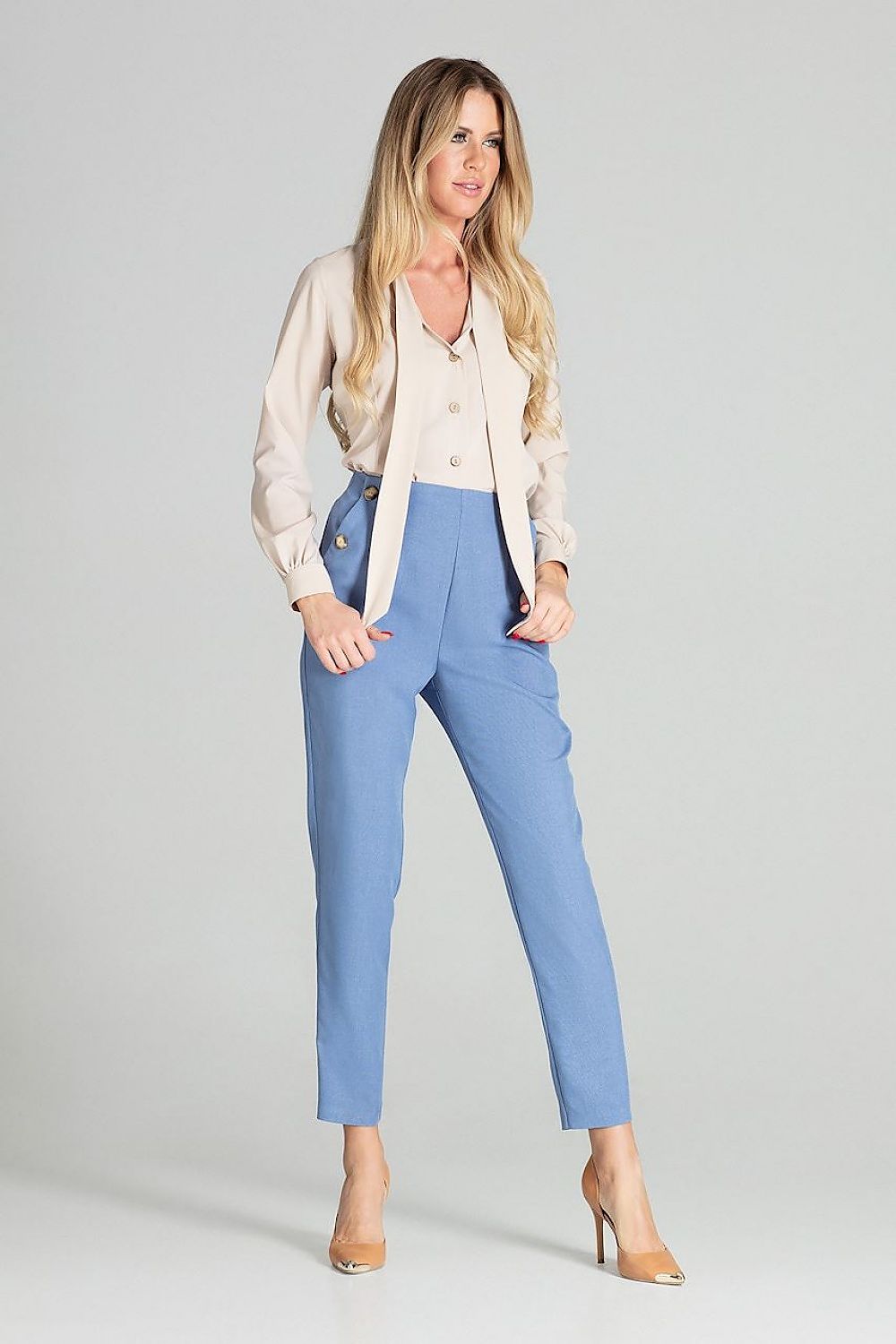 Woman wearing a beige blouse and blue pants on a gray background