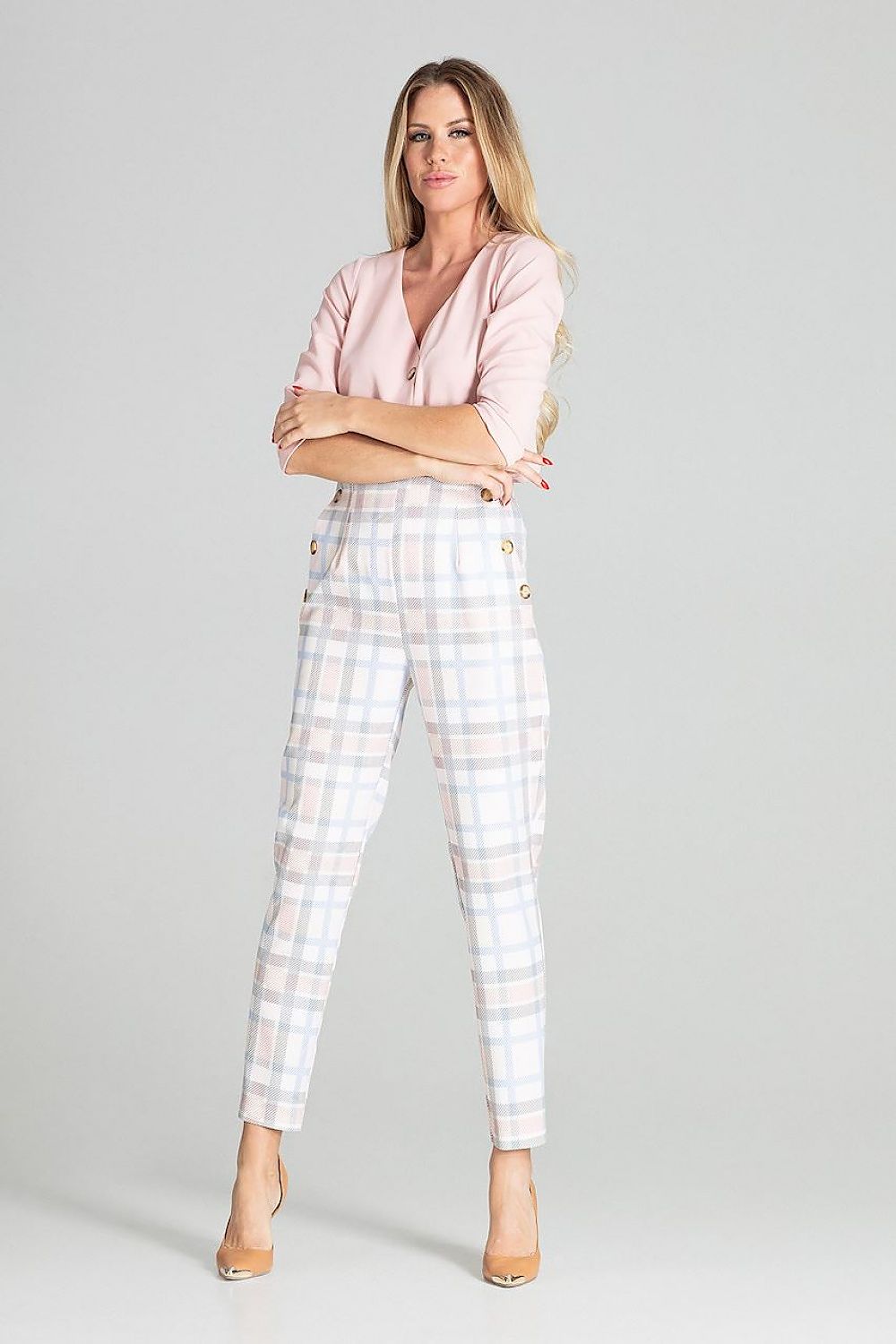 Woman wearing a pink blouse and plaid pants on a gray background