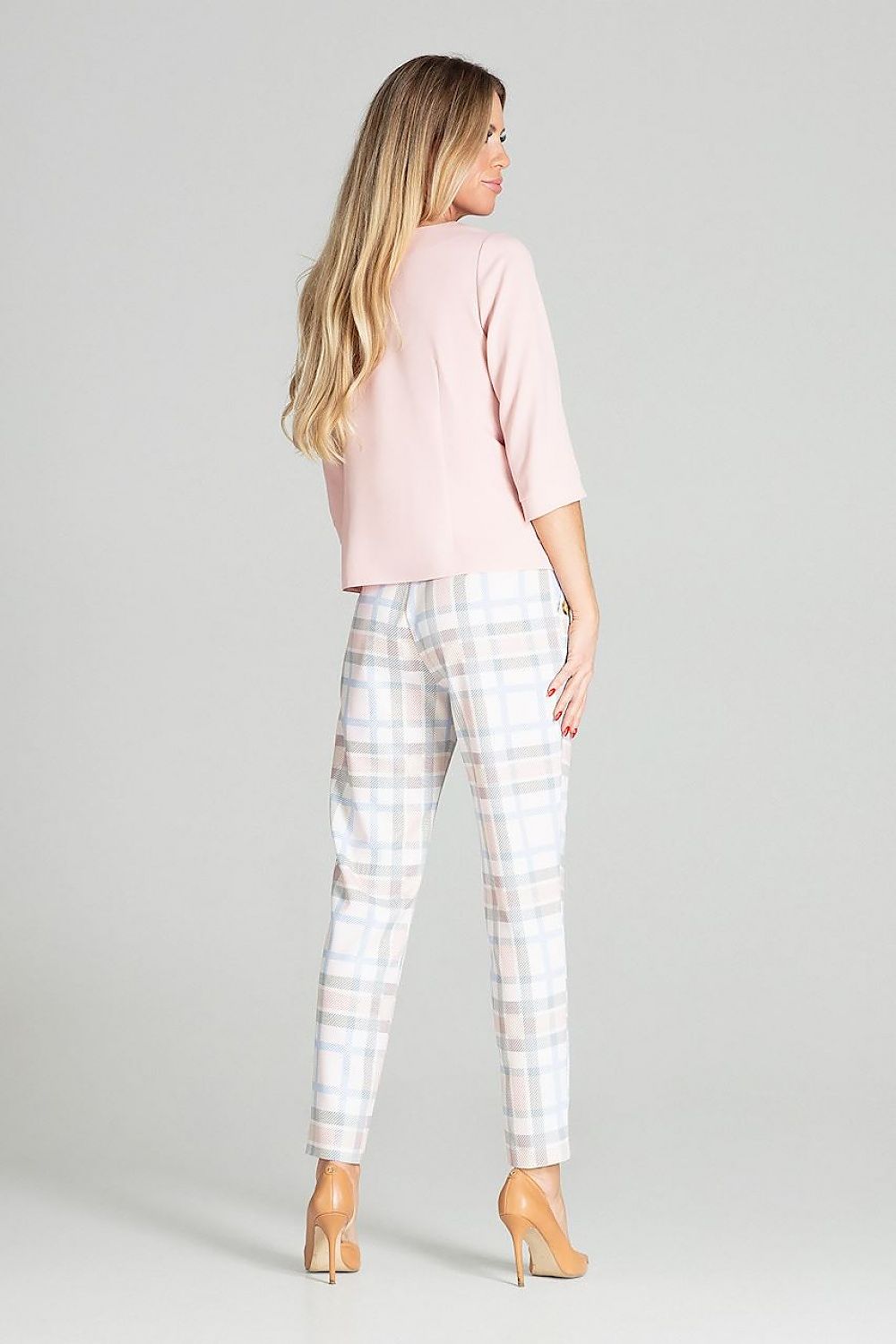 Woman wearing a pink top and plaid pants on a gray background