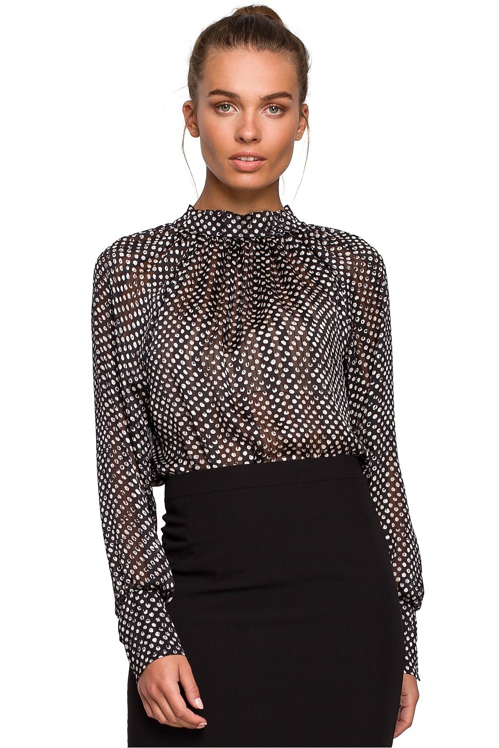 Woman wearing a black and white patterned blouse with a black skirt on a white background
