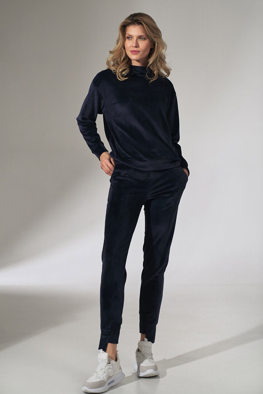 Woman wearing a black outfit with white sneakers on a plain background