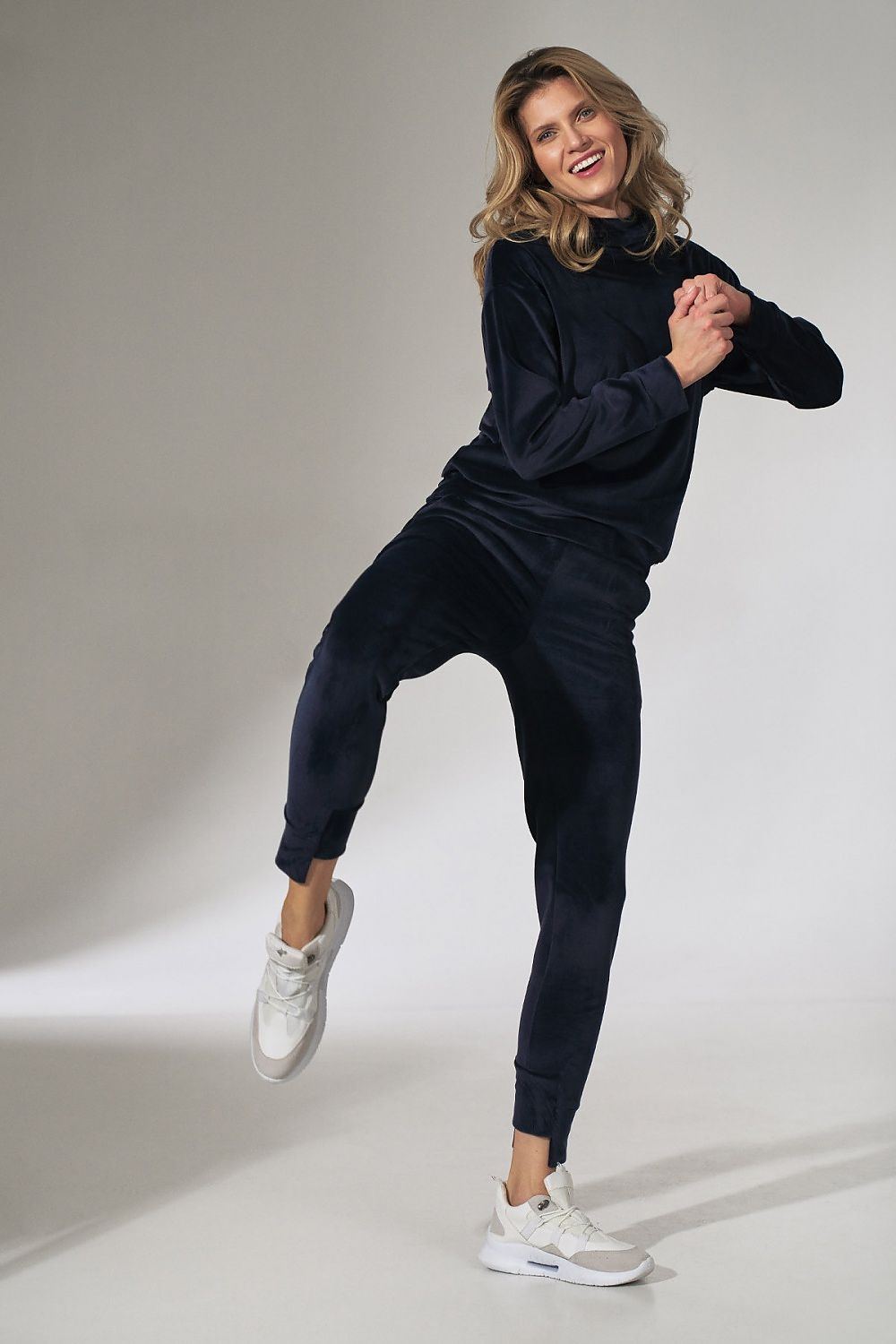 Woman in navy tracksuit posing on a gray background