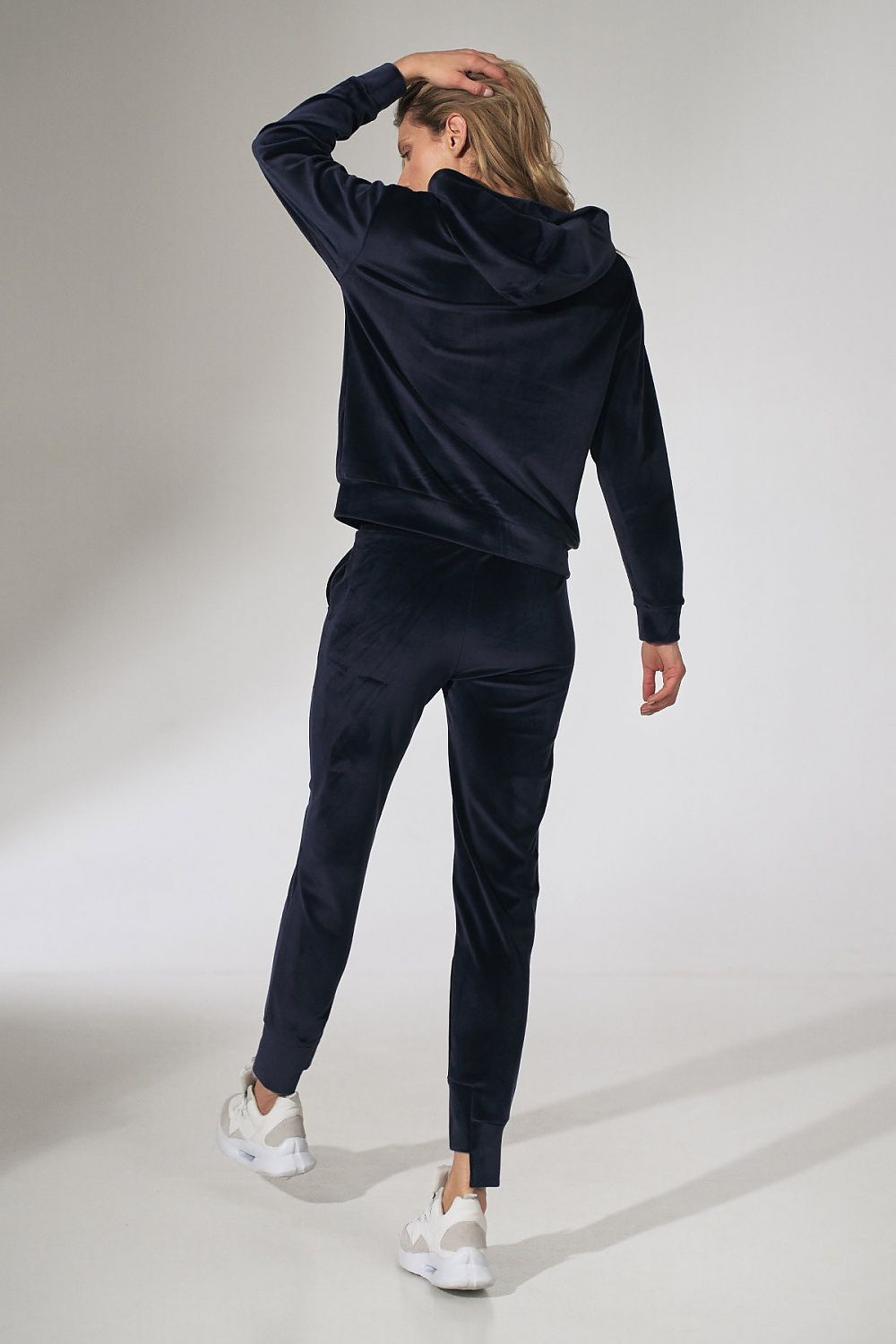 Person wearing a navy tracksuit on a light gray background