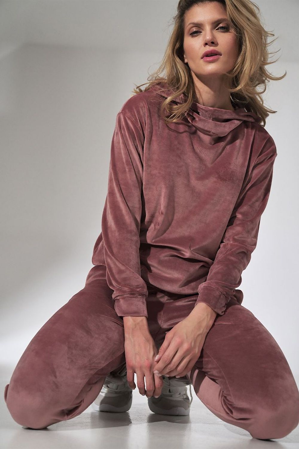 Woman wearing a mauve velvet outfit on a plain background