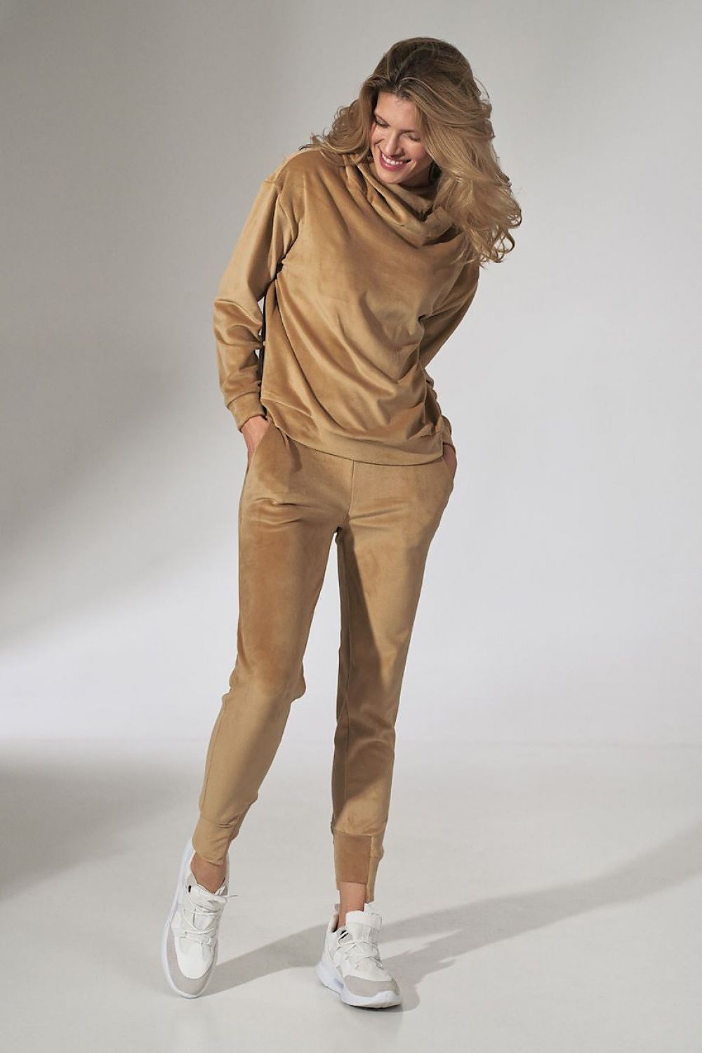 Woman wearing a beige tracksuit on a plain background