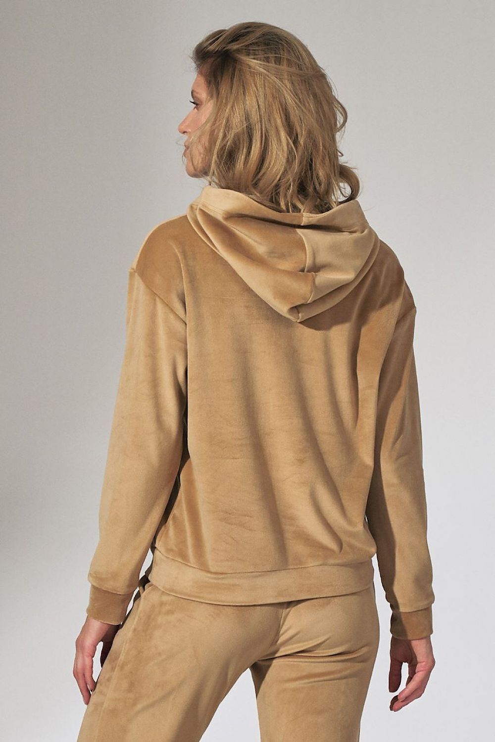 Person wearing a beige hoodie and pants on a plain background