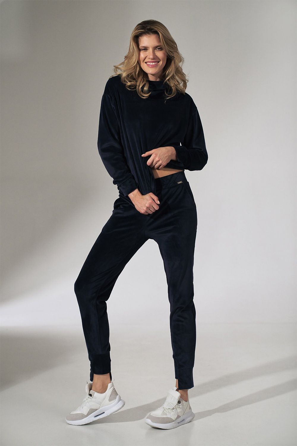 Woman wearing a black outfit with white sneakers on a plain background