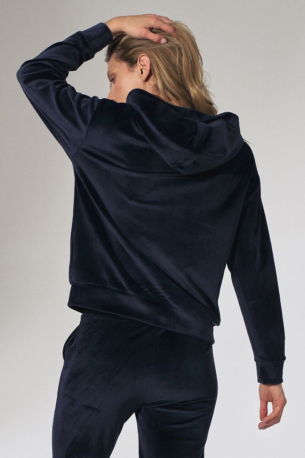Person wearing a navy blue tracksuit against a plain background