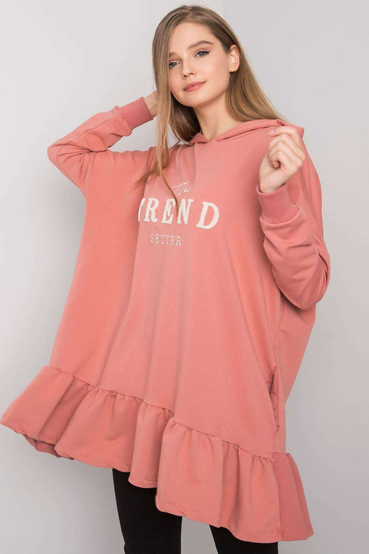 Woman wearing a pink hoodie with ruffled sleeves and bottom on a plain background