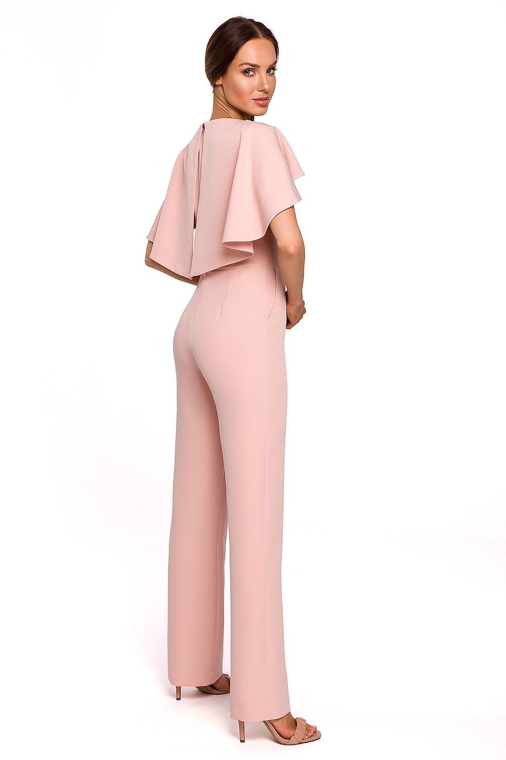 Woman wearing a pink jumpsuit with a cape on a white background