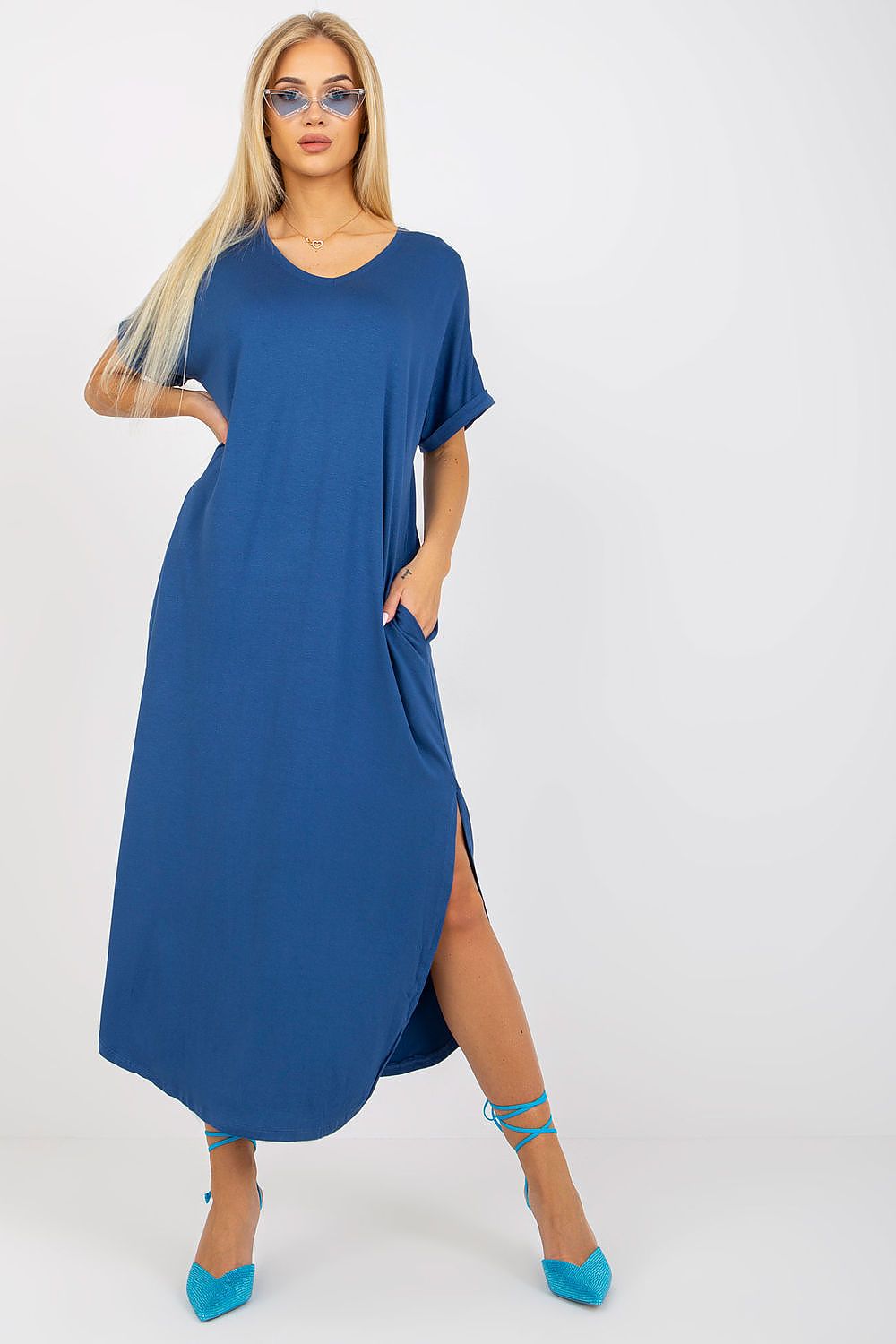Woman wearing a blue dress with a slit on a white background