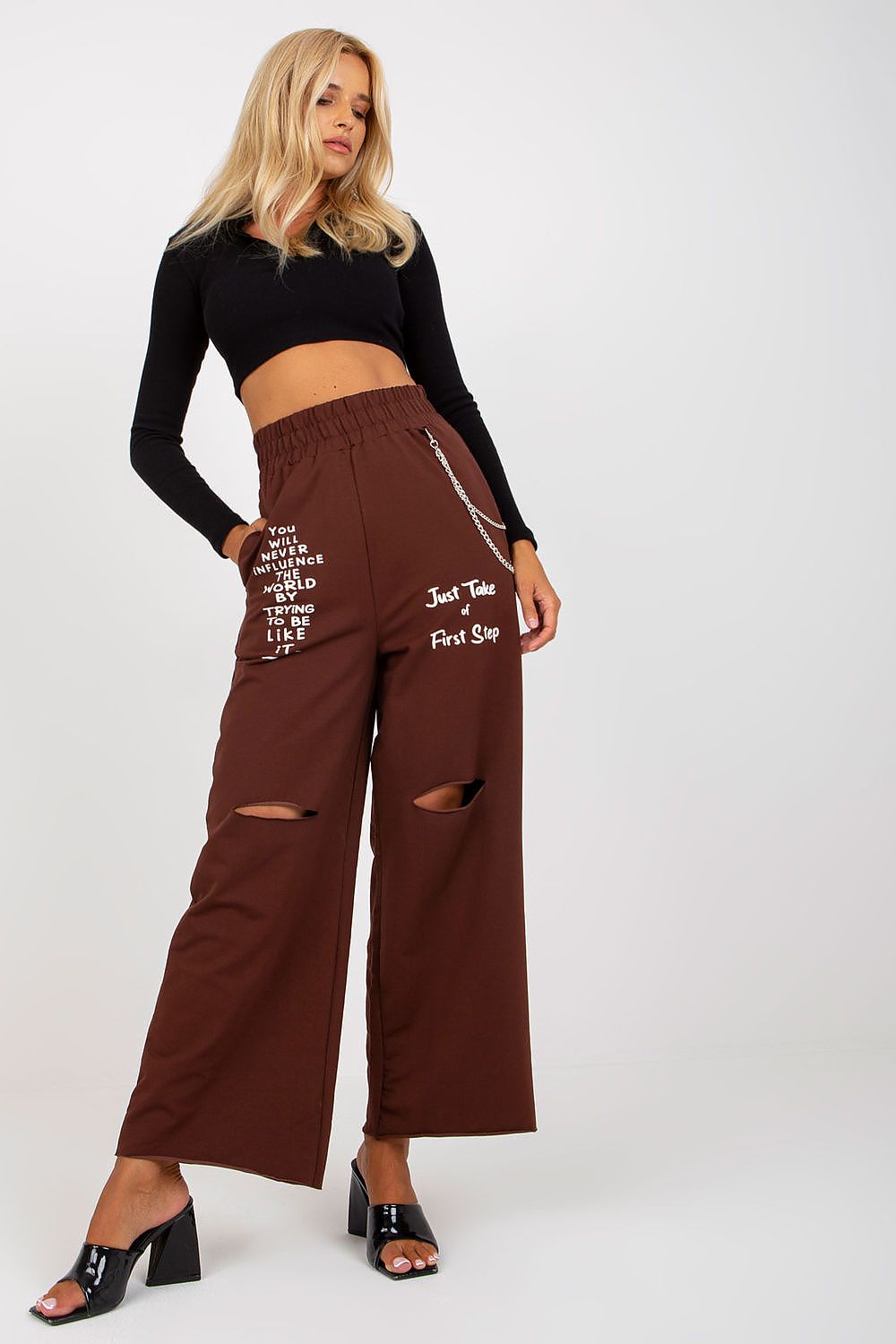 Woman wearing brown wide-leg pants with text and a black top on a white background