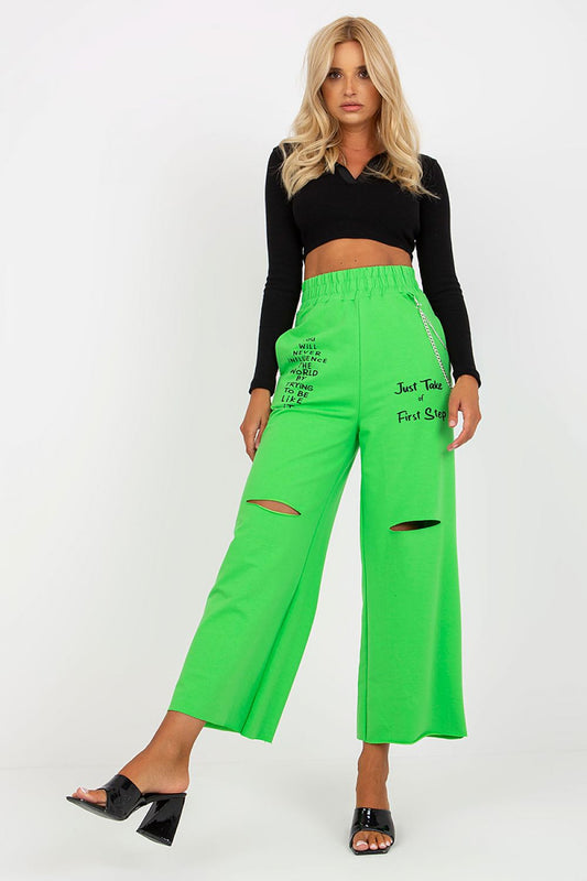 Woman wearing bright green pants with text and a black top on a white background