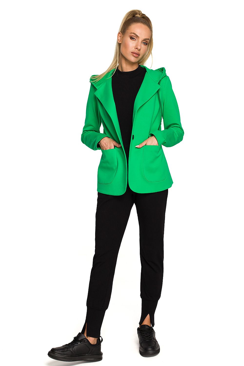 Person wearing a bright green jacket and black pants on a white background