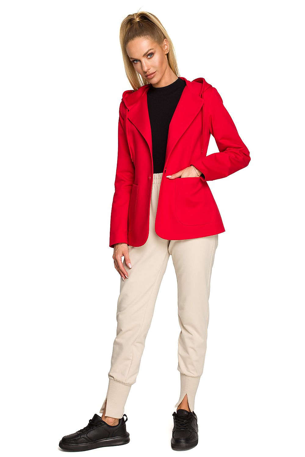 Woman wearing a red blazer, black top, beige pants, and black shoes on a white background