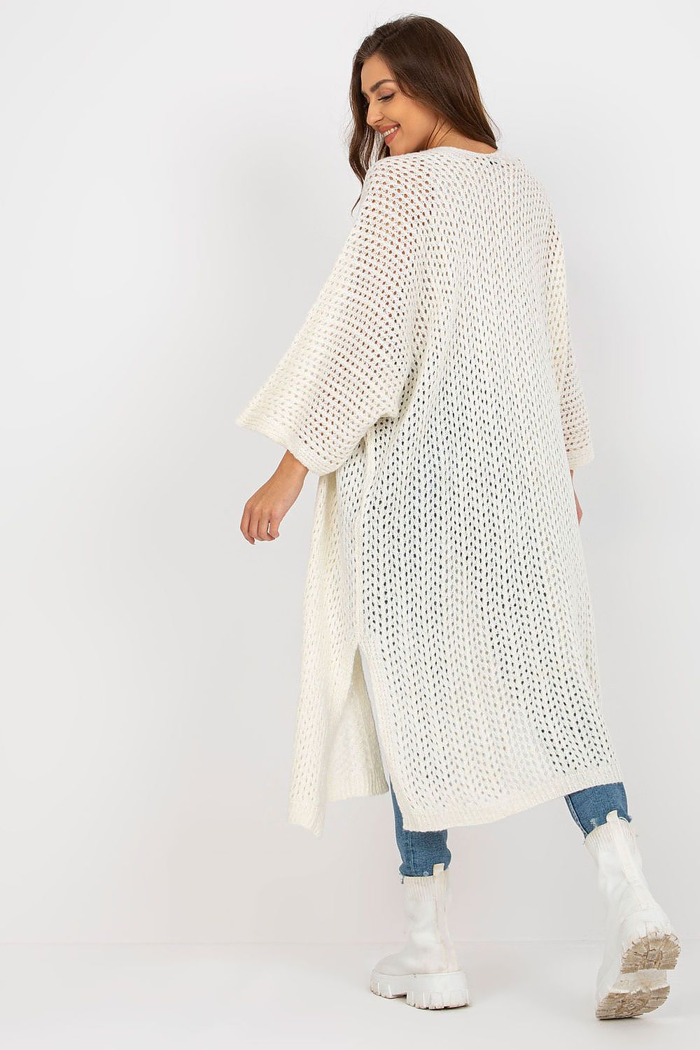Woman wearing a long, light-colored knitted cardigan on a white background