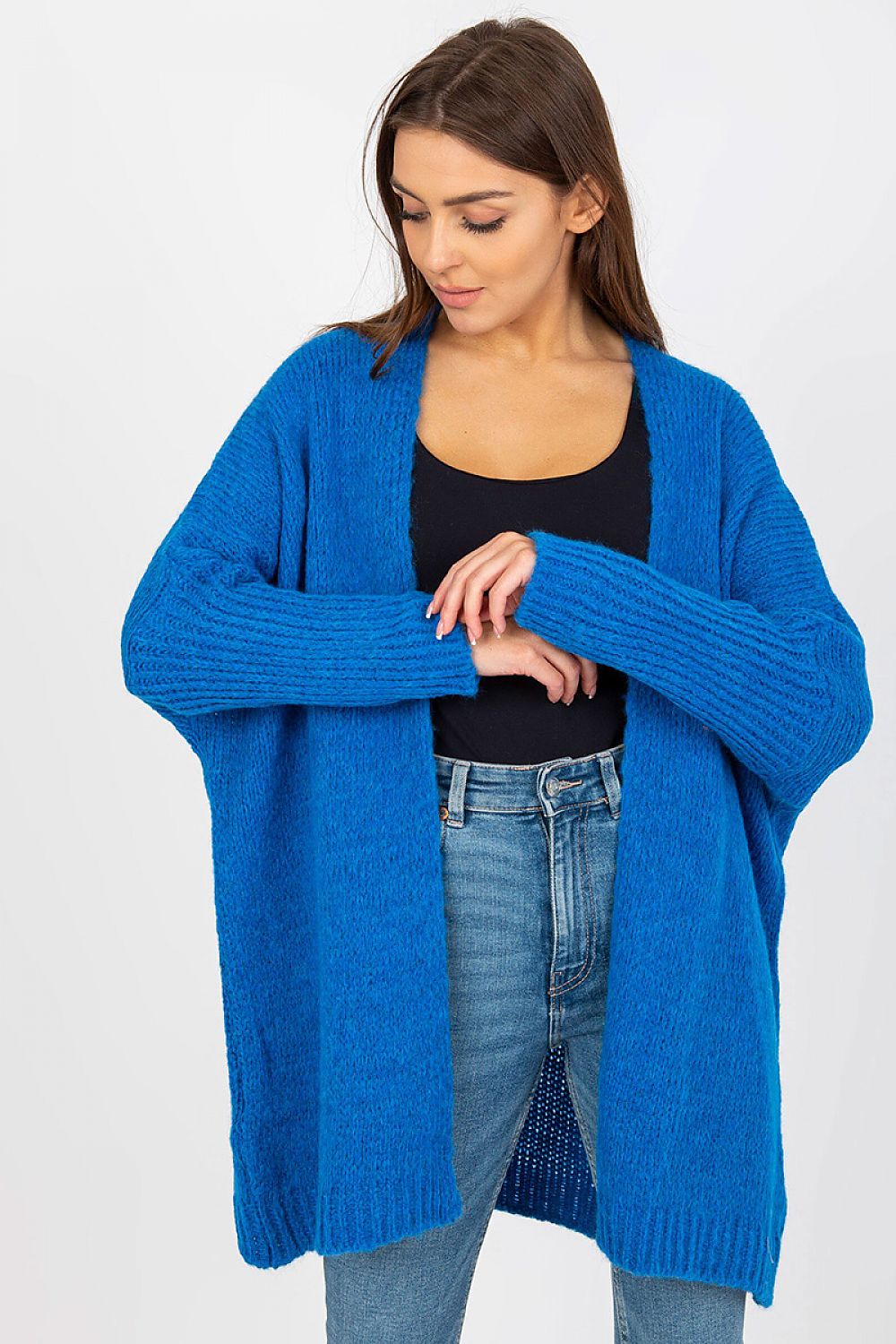 Woman wearing a blue cardigan over a black top and jeans on a white background