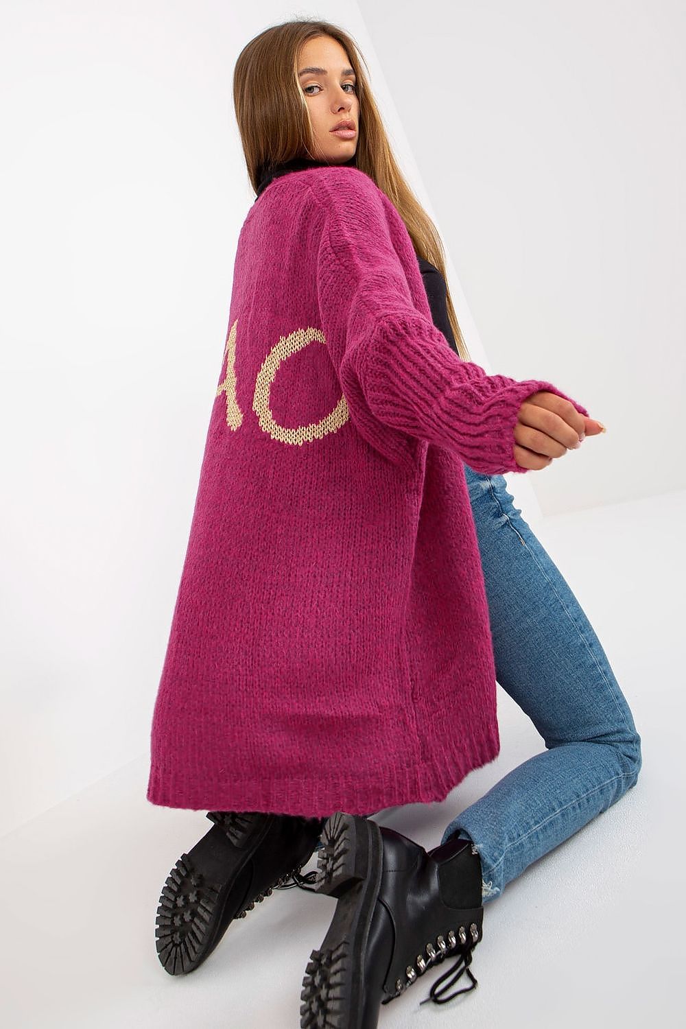 Person wearing a long pink cardigan with 'LOVE' printed on it, standing against a white background.