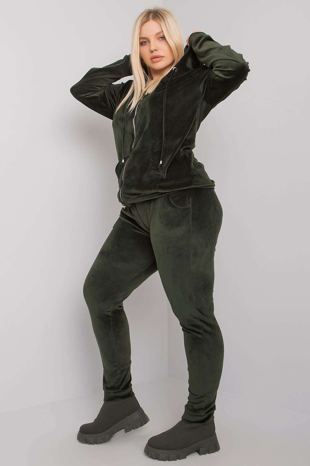 Person wearing a green tracksuit with black boots on a white background