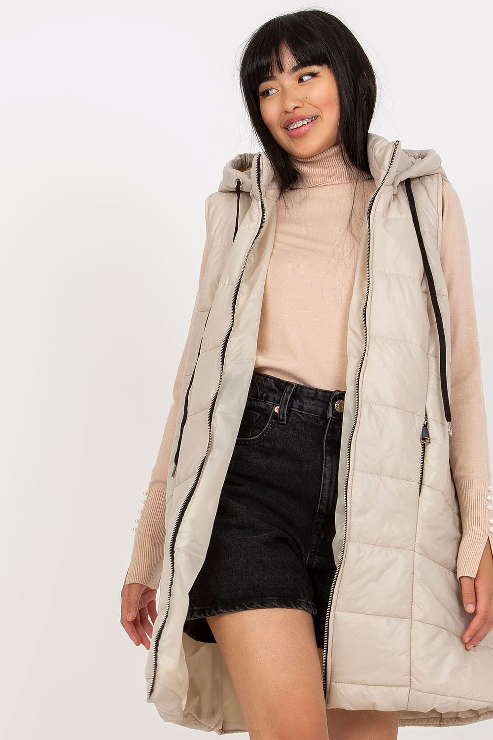 Woman wearing a beige quilted jacket on a white background