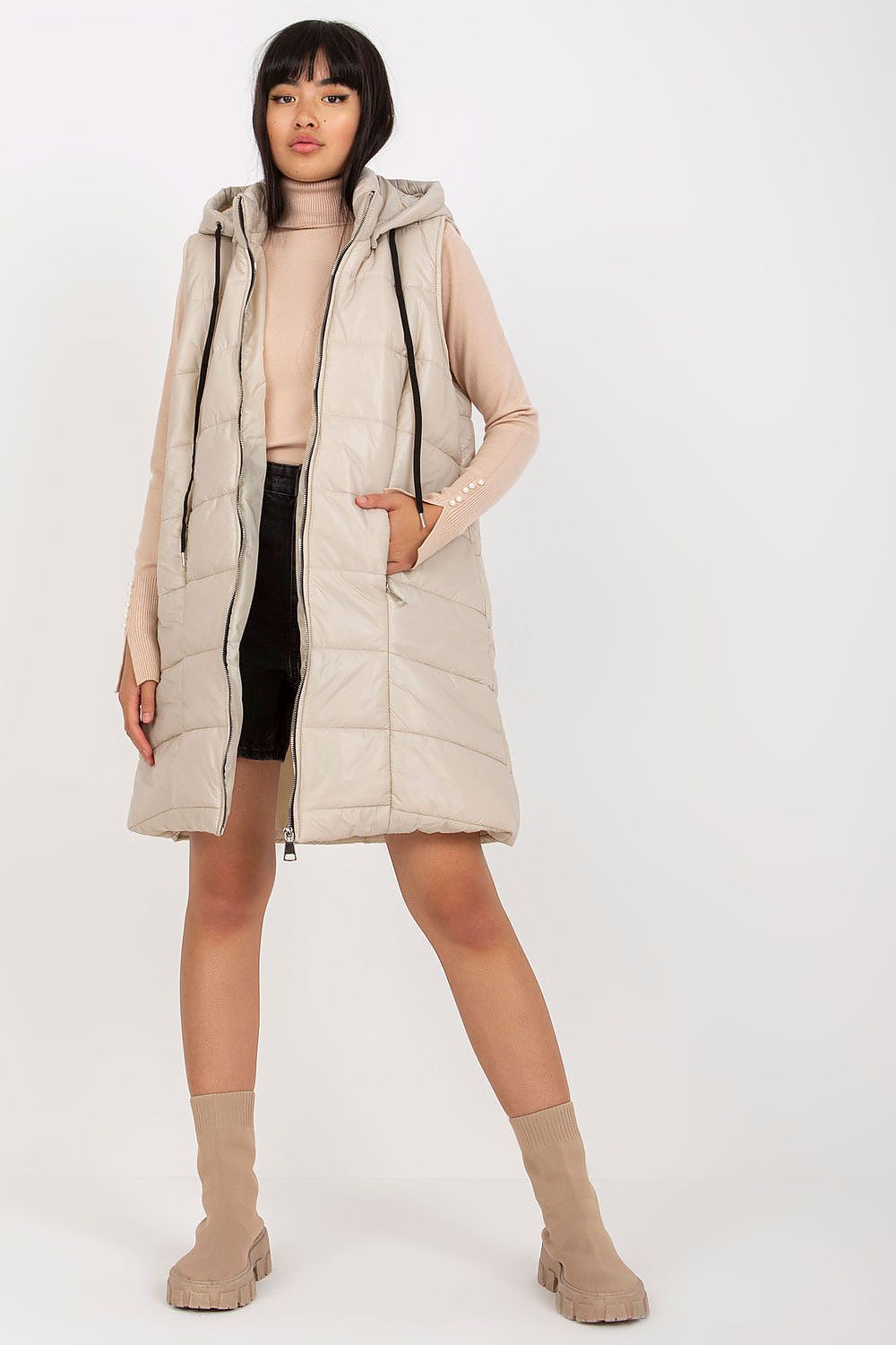 Woman wearing a beige puffer coat on a white background