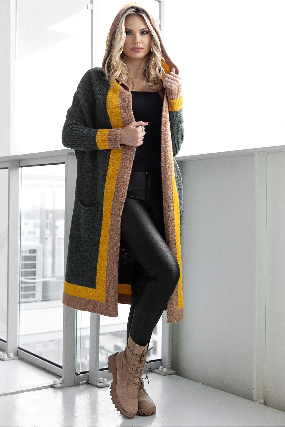 Woman wearing a long, patterned cardigan with a neutral background