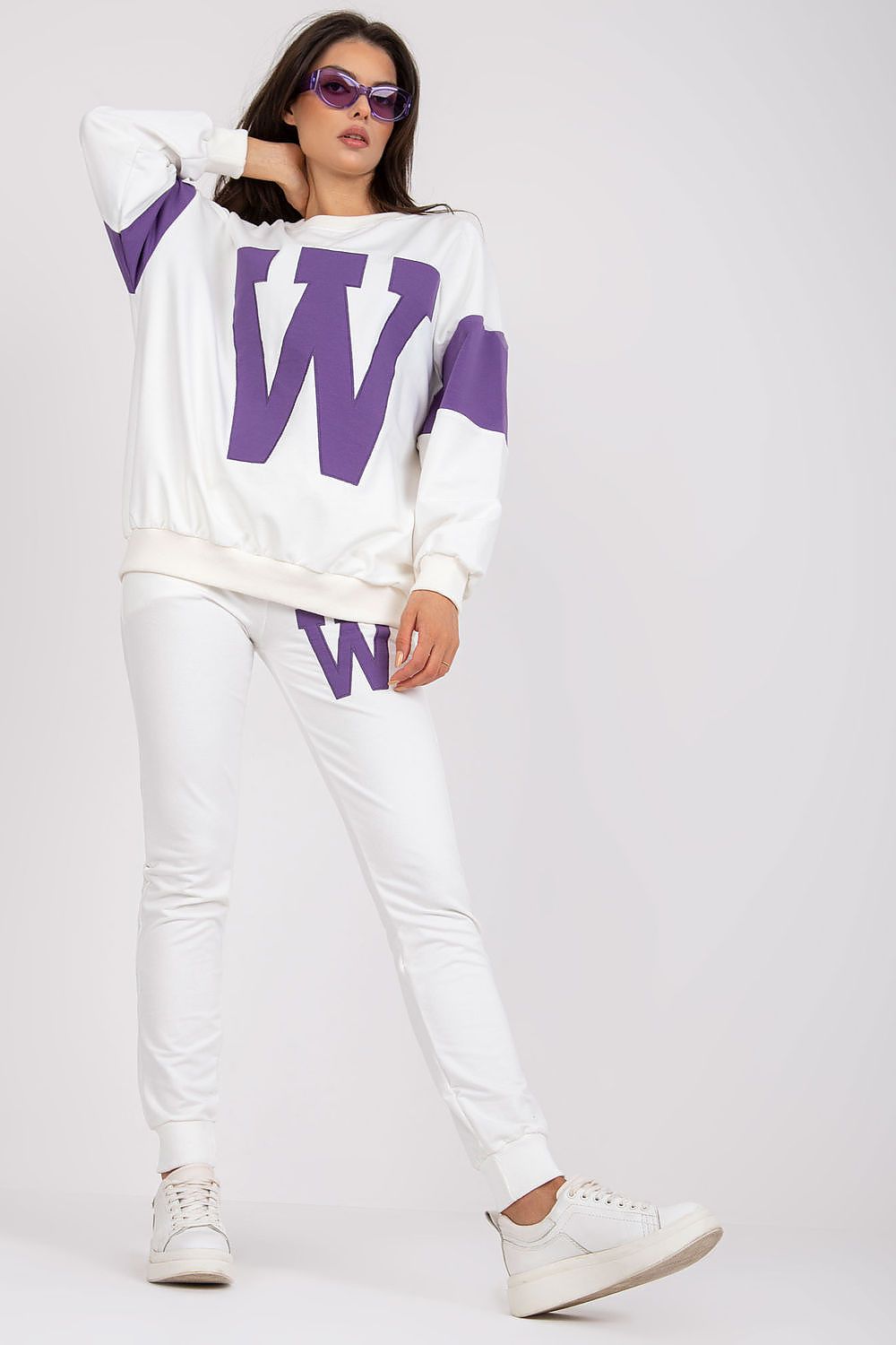 Woman wearing a white and purple outfit with 'W' logo on a plain background