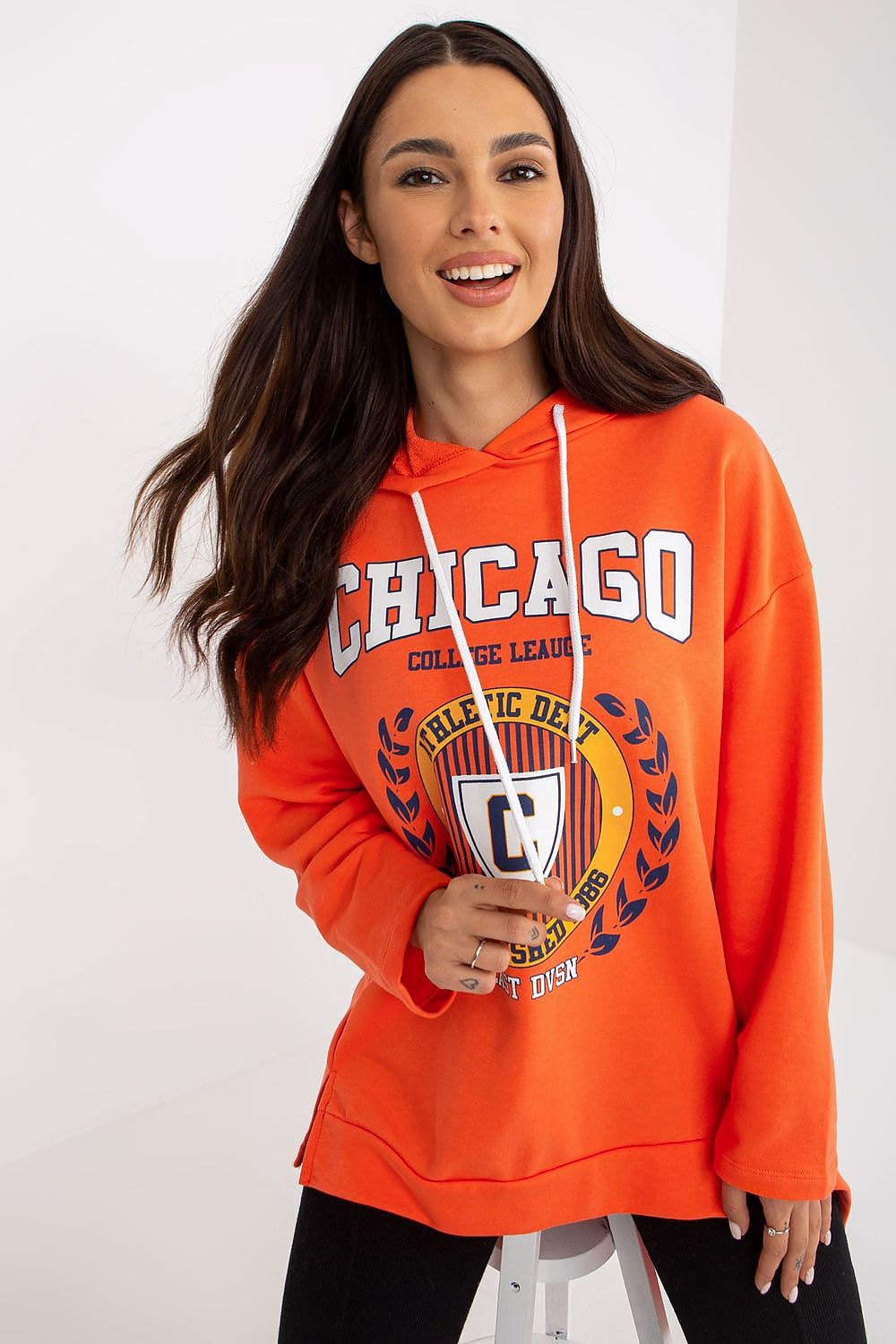 Woman wearing an orange 'Chicago' hoodie with a logo on a white background