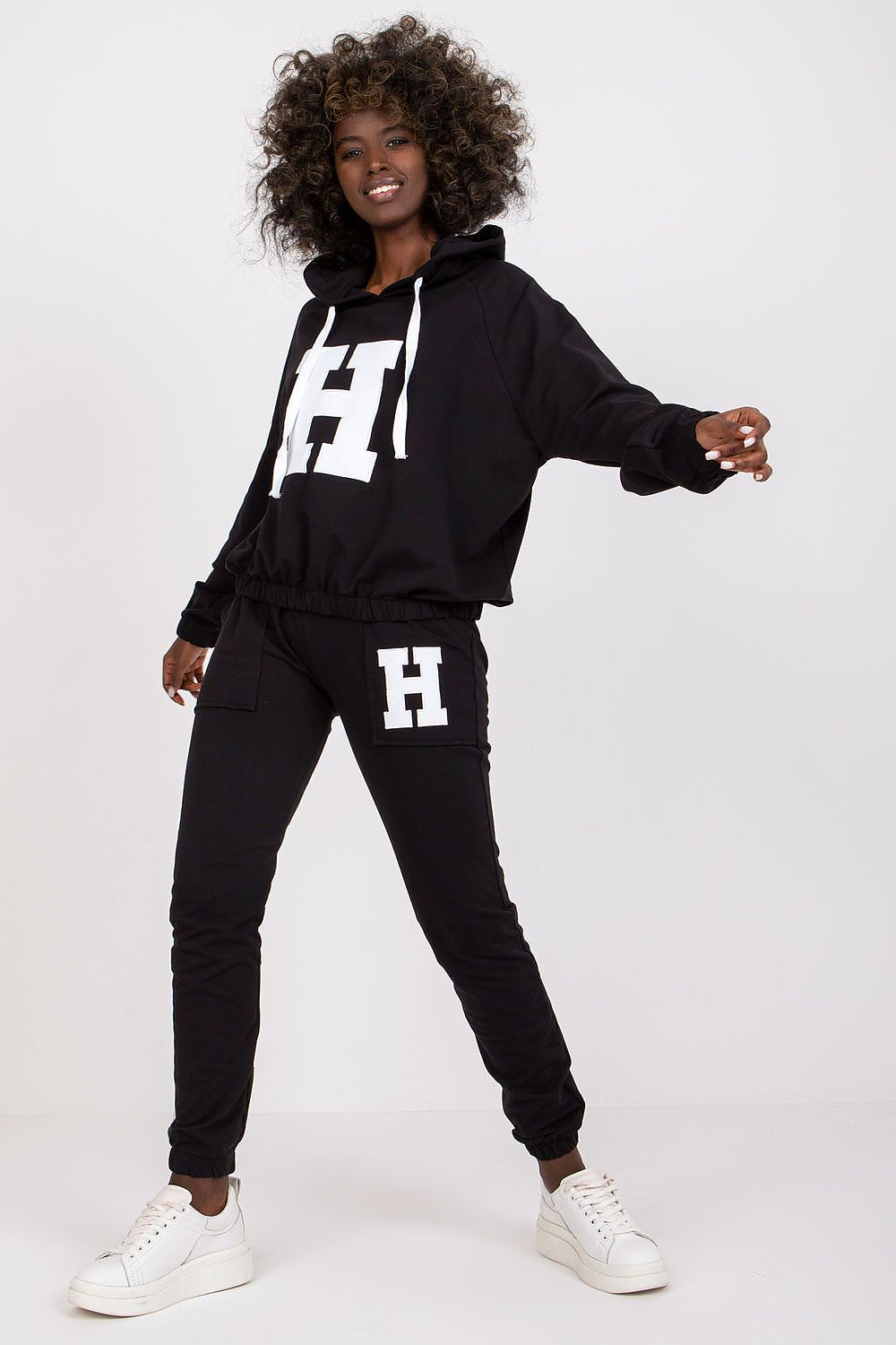 Woman wearing a black tracksuit with 'H' logo on a white background
