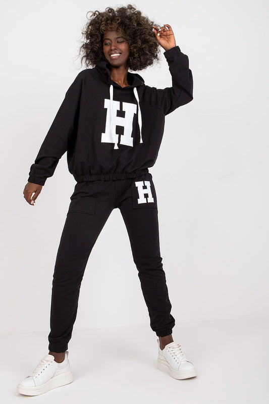 Person wearing a black tracksuit with 'H' logo on a white background