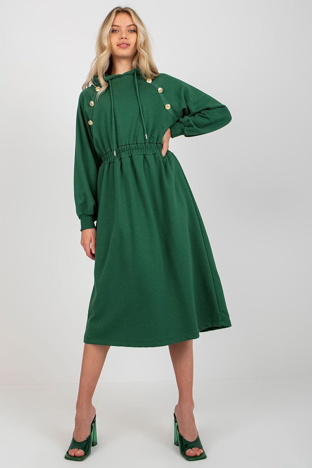Woman wearing a green dress with gold buttons on a white background