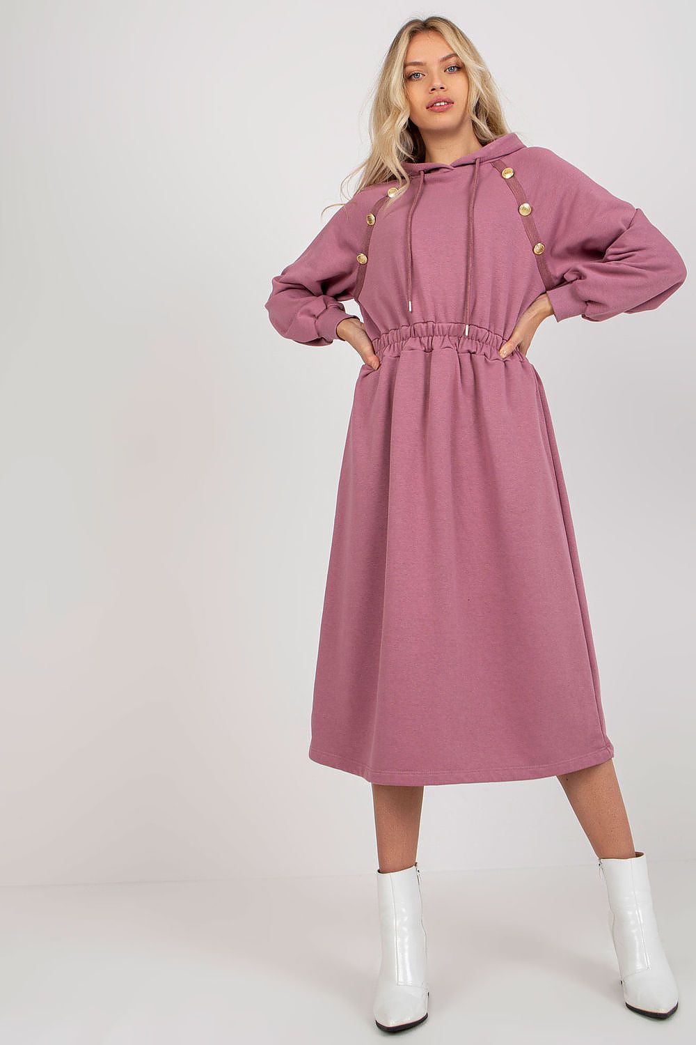 Woman wearing a pink dress with button details on a white background