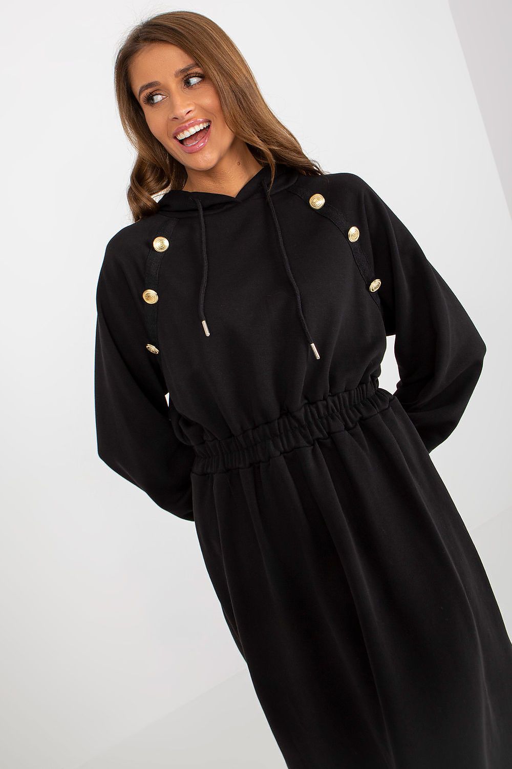 Woman wearing a black dress with gold buttons on a white background