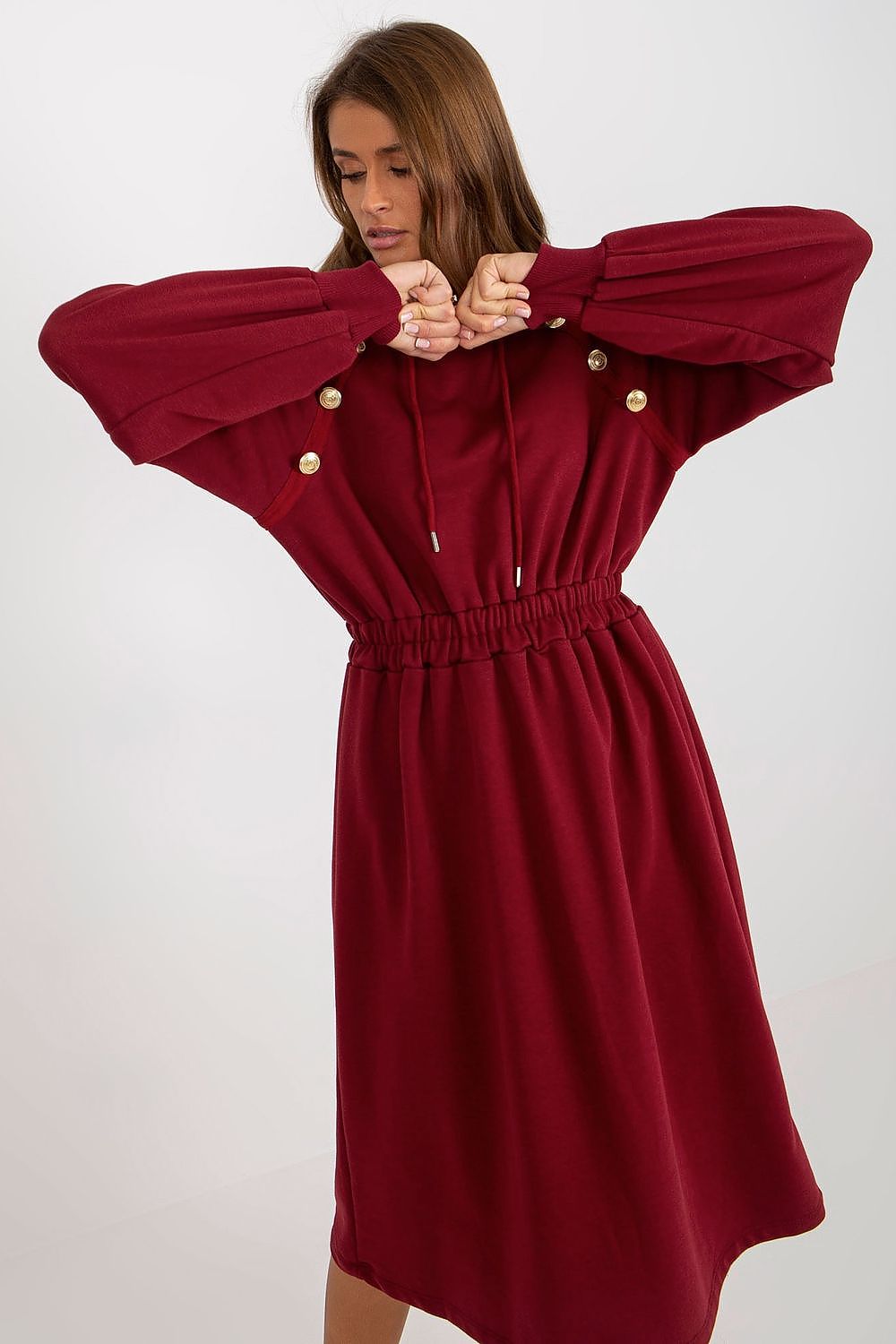 Red dress with gold buttons worn by a person on a white background