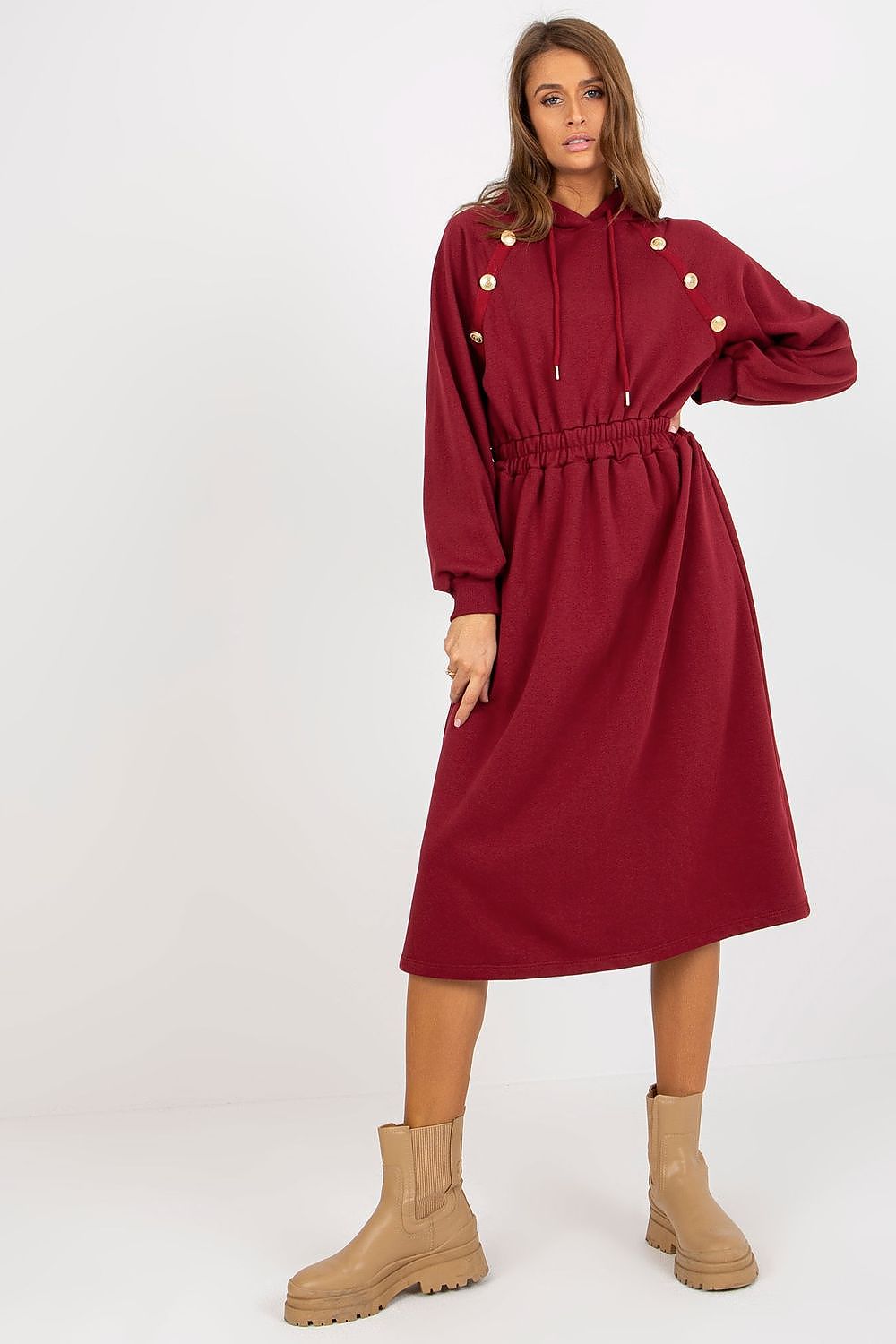 Woman wearing a burgundy dress with button details on a white background