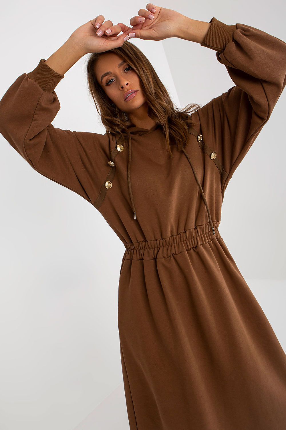Woman wearing a brown dress with button details on a white background
