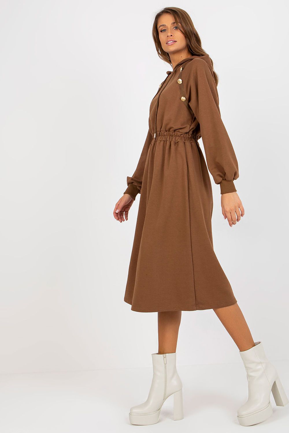 Woman wearing a brown dress with white boots on a white background