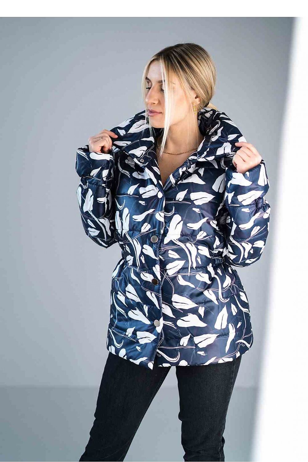 Person wearing a navy blue jacket with white floral patterns on a gray background