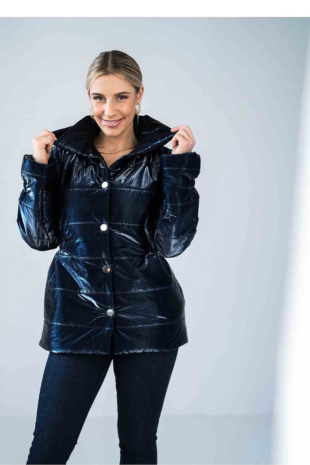 Woman wearing a shiny black jacket against a light gray background