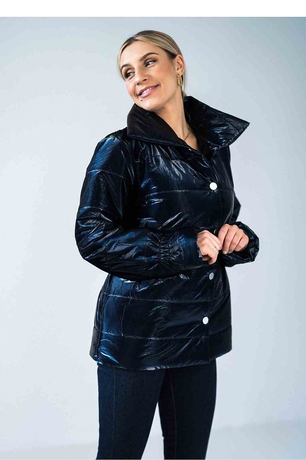 Woman wearing a black puffer jacket against a light gray background