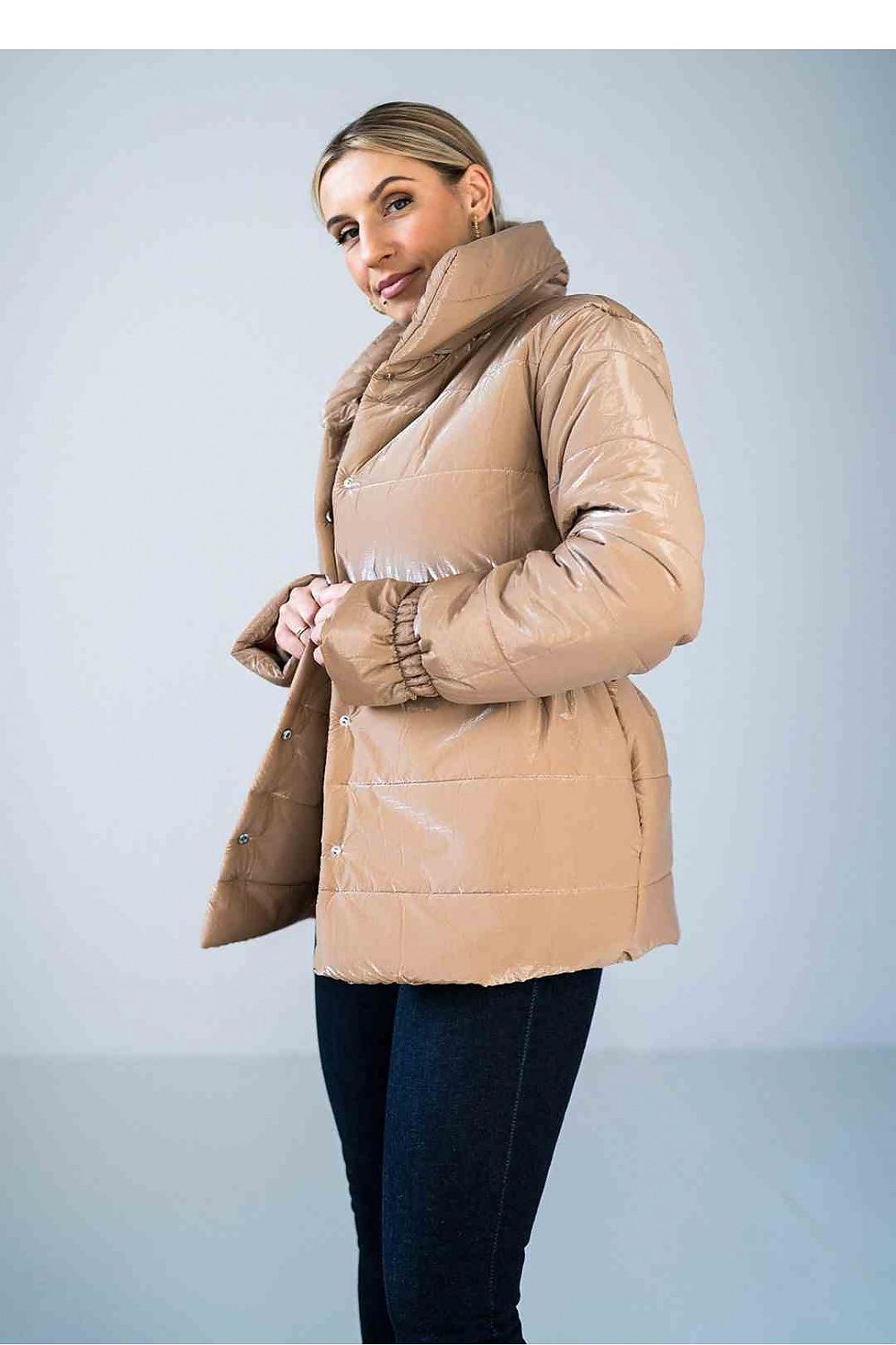 Woman wearing a beige puffer jacket against a light blue background