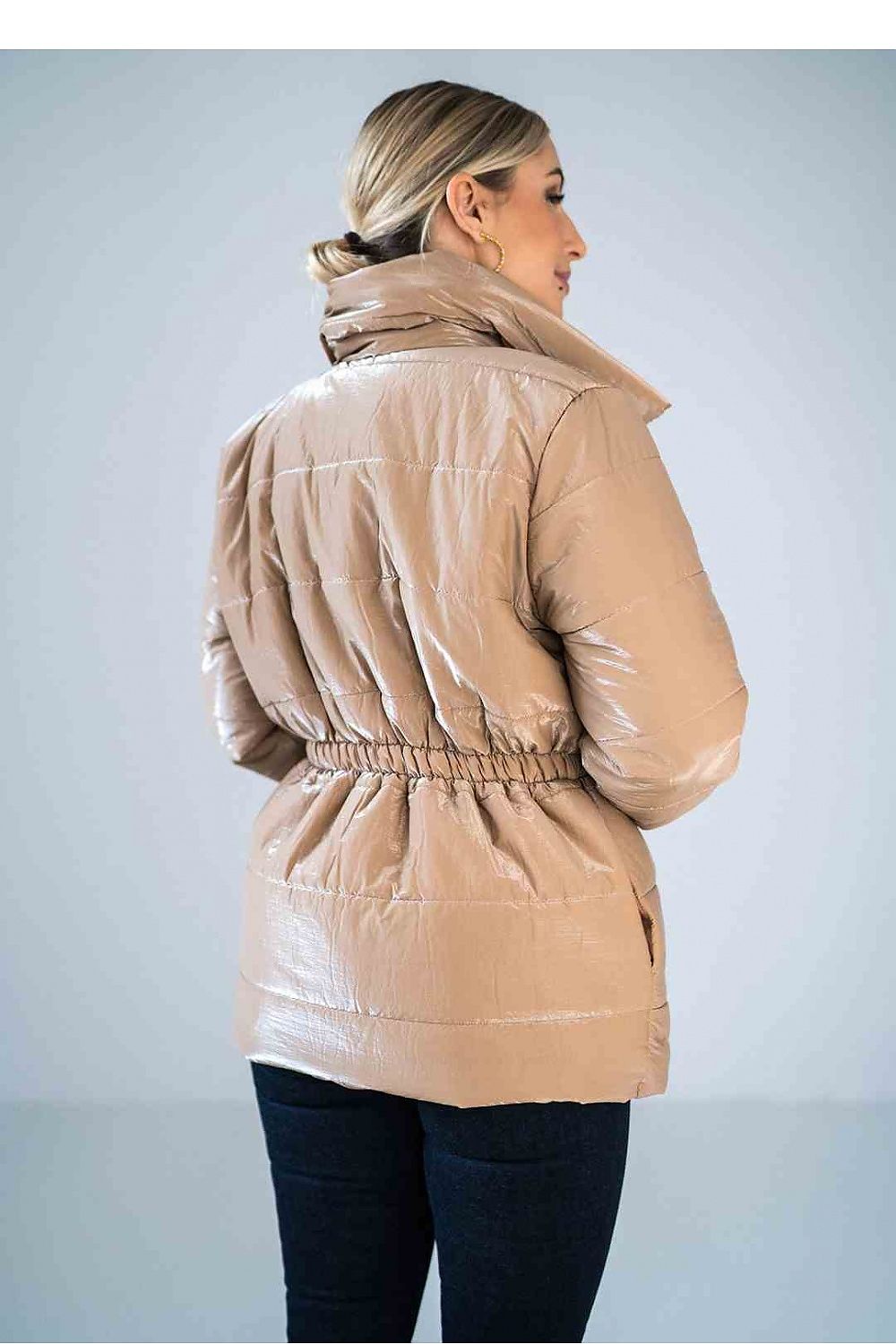 Woman wearing a beige puffer jacket against a light gray background