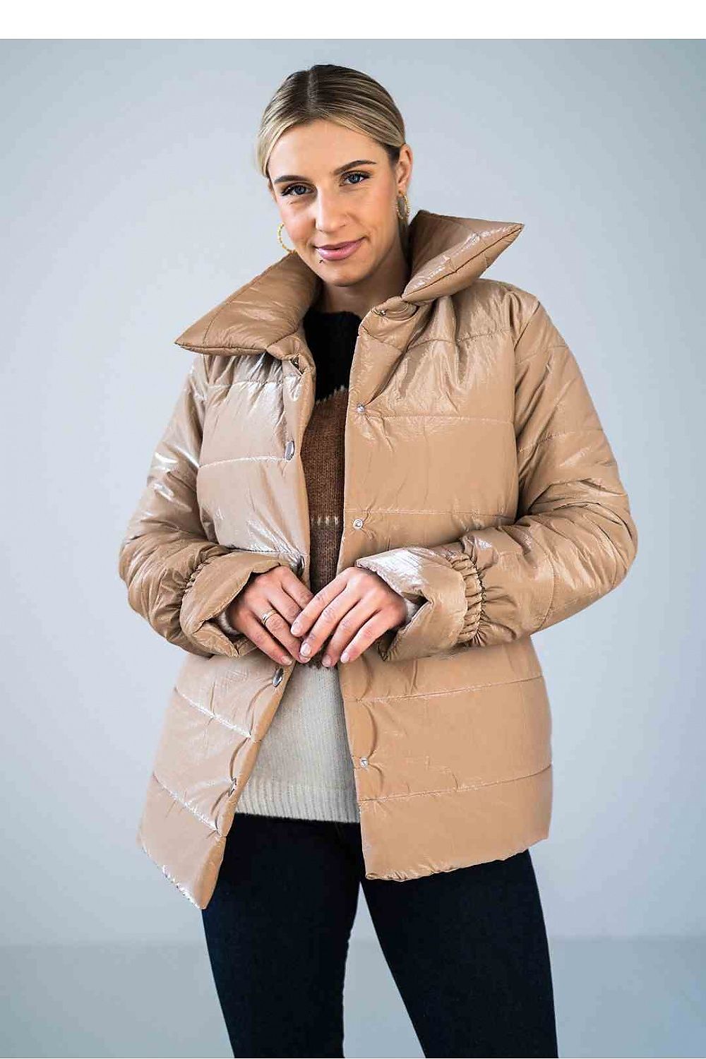 Woman wearing a beige puffer jacket against a light gray background