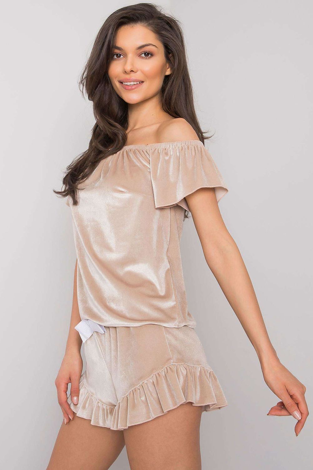 Woman wearing a beige satin nightgown against a plain background