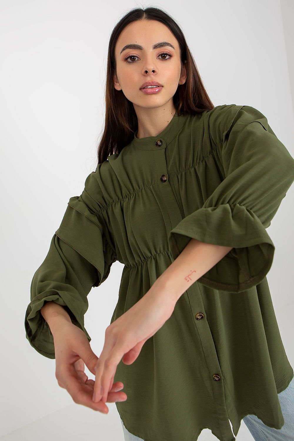 Woman wearing an olive green dress with long sleeves against a white background