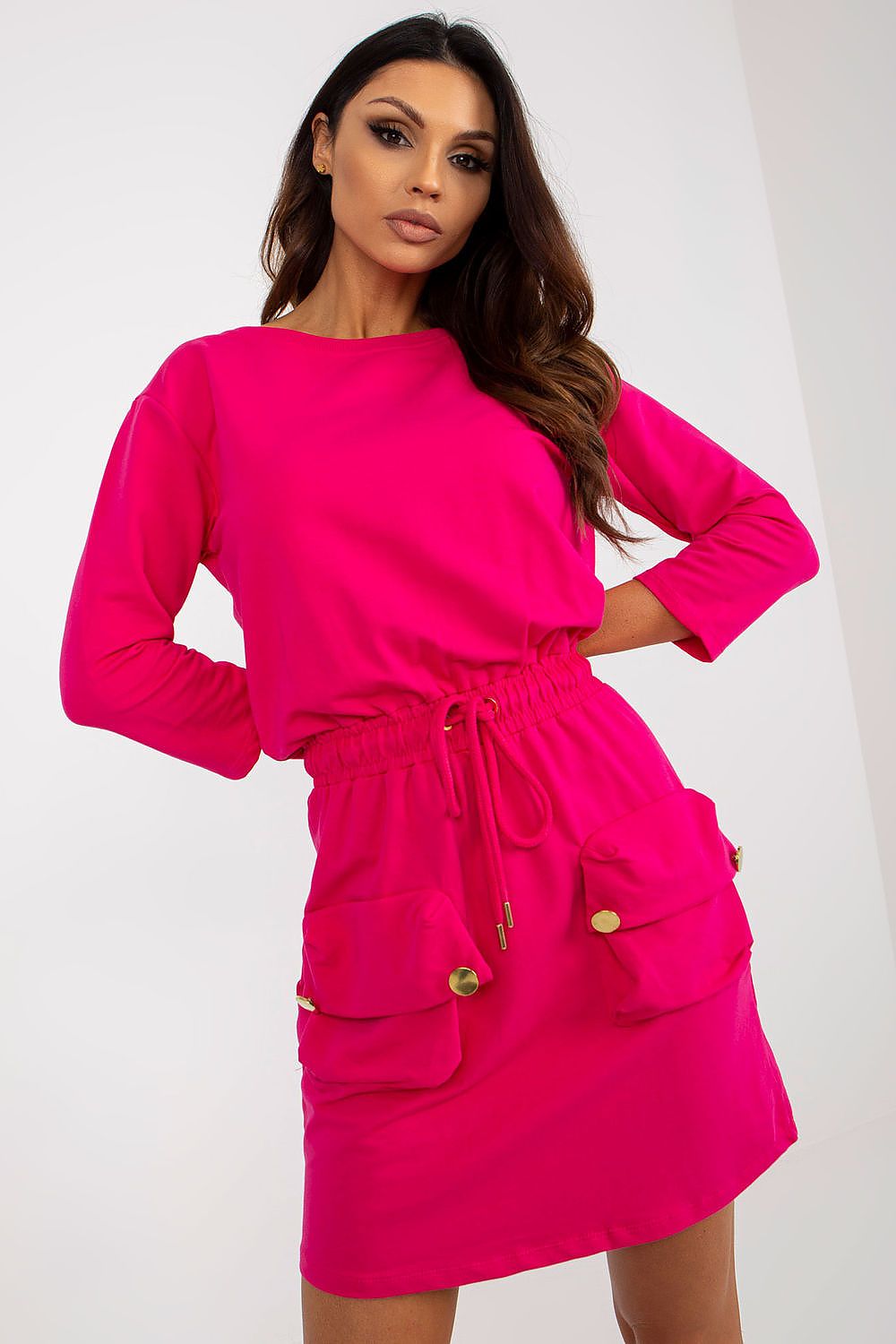 Woman wearing a bright pink dress with long sleeves on a white background