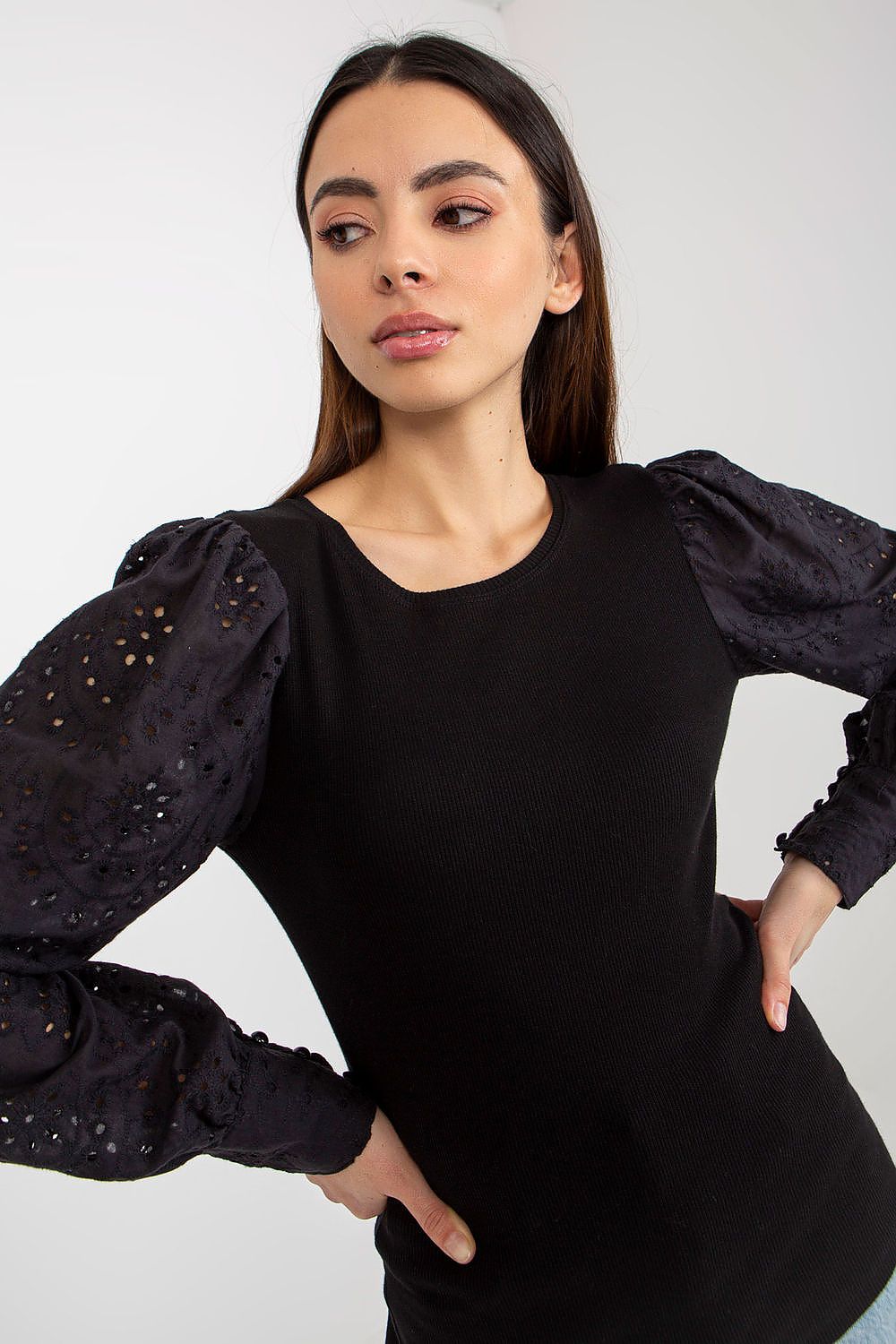 Woman wearing a black dress with embellished sleeves against a white background