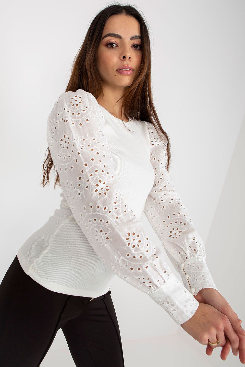 Woman wearing a white lace blouse against a plain background